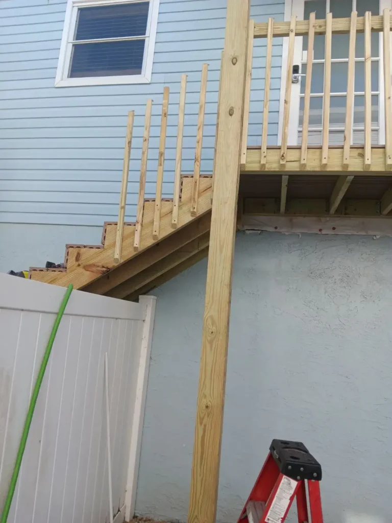 A cat is sitting on the steps of a house.