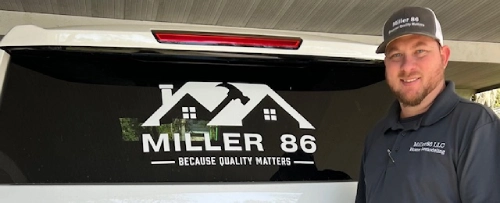 Man standing beside branded vehicle logo.
