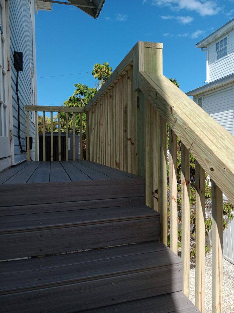 A wooden deck with steps and railing on the side.