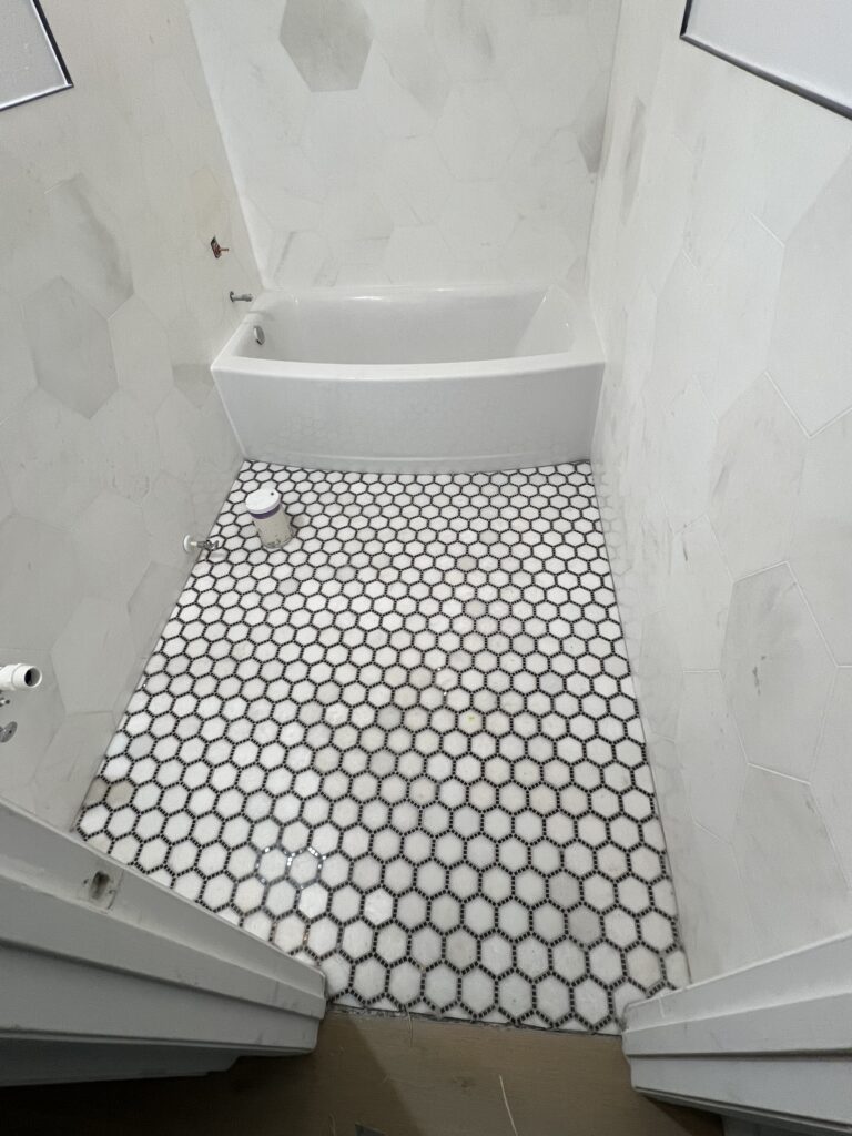 A bathroom with white walls and black and white tile.