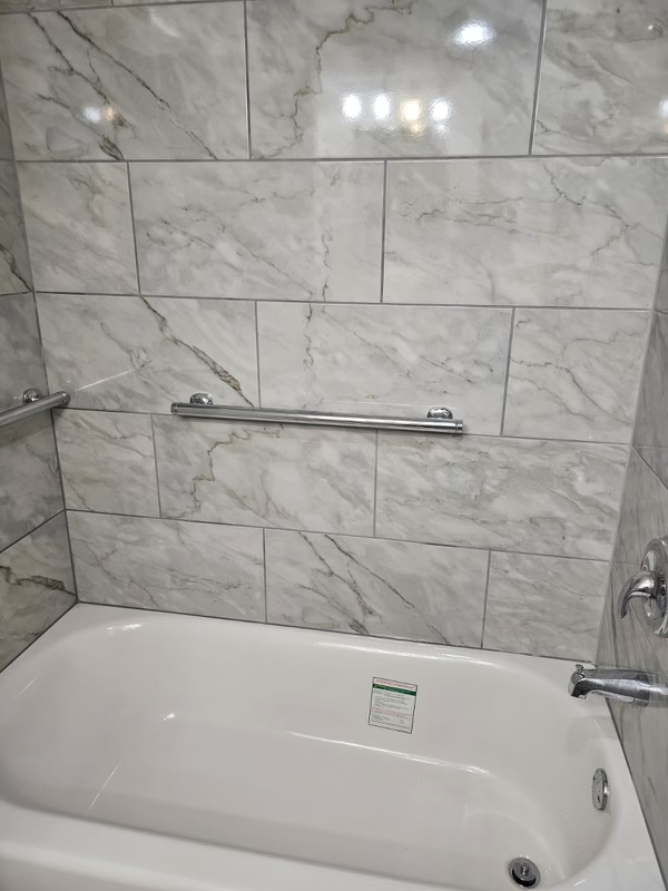 A bathroom with marble tile and white walls.